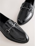 Paar zwarte glanzende loafers met zilverkleurige gespen.