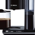 Zwarte Bosch koffiemachine met glazen kan met koffie en transparante waterreservoir.