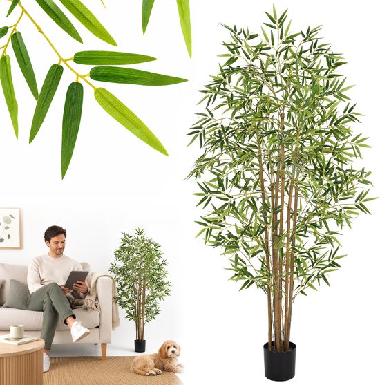 Een kunstmatige bamboeplant in een zwarte pot, naast een bank waar een man op zit.