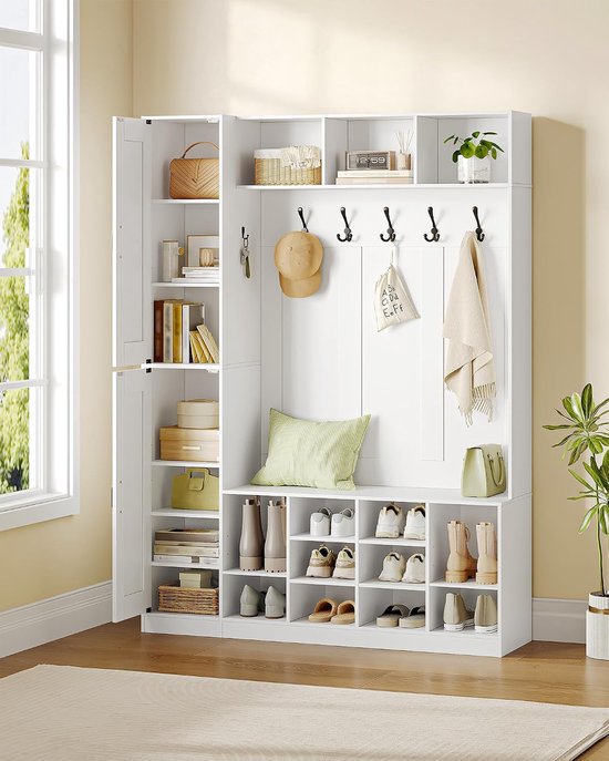 Witte halmeubel bij een raam. Links hoge kast, midden 6 haken, schoenenbank met schoenen, rechts schoenen.