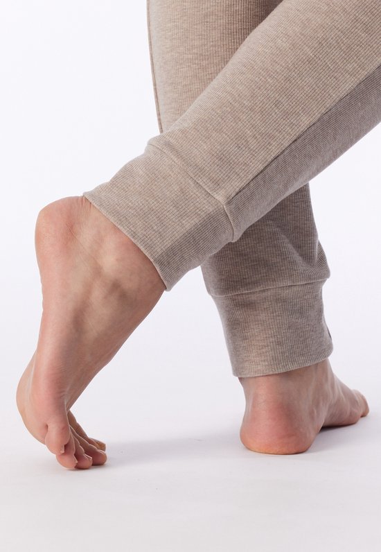Detailopname van de onderkant van een beige, geribbelde pyjamabroek met boorden bij de enkels.