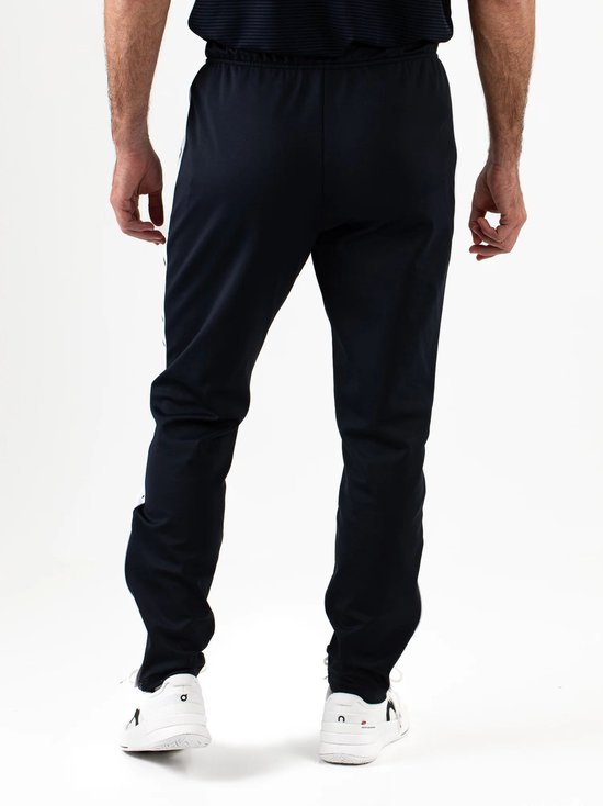 Achterkant van een man die een donkerblauwe trainingsbroek met witte strepen op de zijkant draagt.