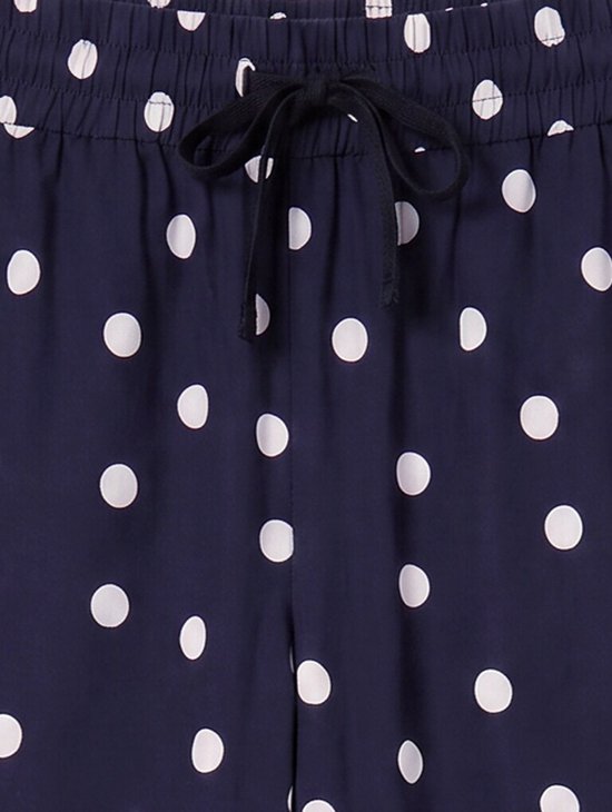 Sluiting van de marineblauwe culotte met witte polkadotprint, elastische tailleband en zwarte strikceintuur.