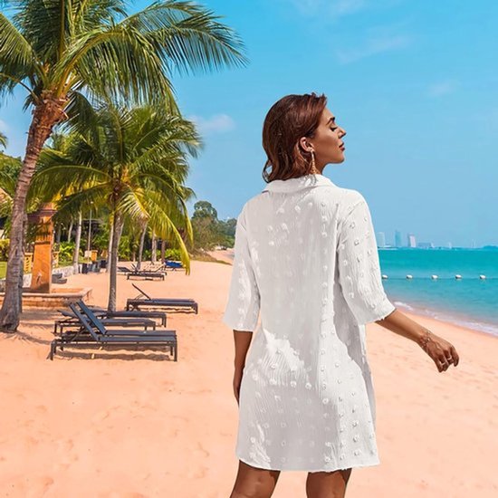 Witte chiffon strandtuniek met pom-pom details, driekwart mouwen en openvallende kraag.