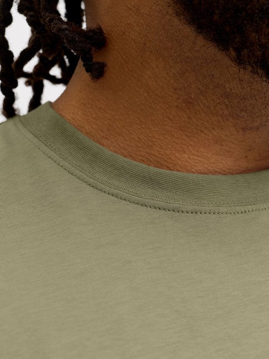 Close-up van de nek van een man die een olijfgroen T-shirt draagt.