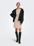 Model met beige gebreide jurk met kabelpatroon en zwarte leren jas.