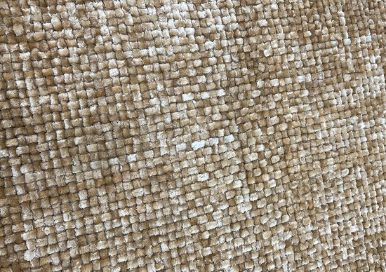 Close-up van een zandkleurig badmat met een textuur van kleine, zachte lussen.