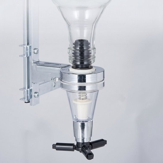 Een close-up van een chromen drankdispenser met glazen reservoir en zwarte hendel.