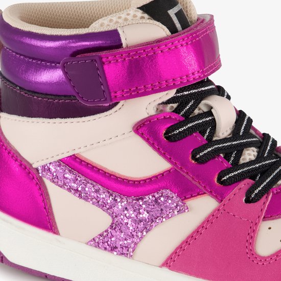 Close-up van roze hoge sneaker met paarse en crèmekleurige accenten, glitterdetails en klittenbandsluiting.