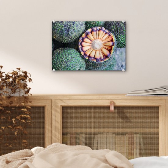 Een glas schilderij van Braziliaans fruit hangt boven een houten kast. De print toont de doorgesneden vrucht met groene schubben.