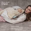 Vrouw met trui omarmt een Sandstone Beige Zenwave warmtekussen. Ideaal voor spierspanning, zoals rugpijn. Geniet en ontspan.