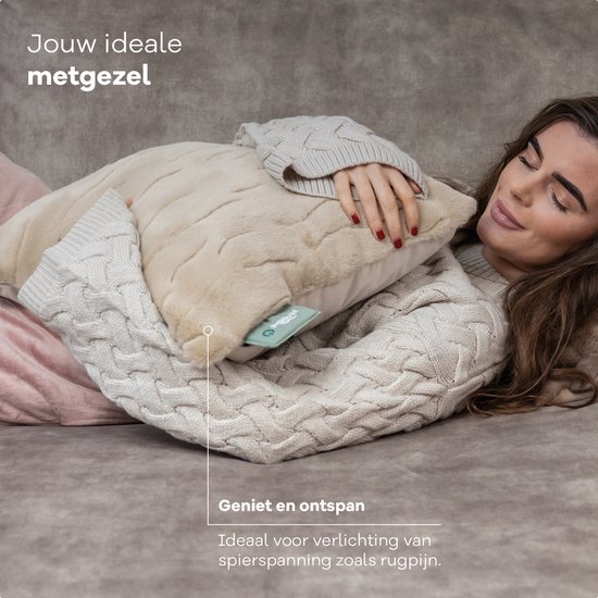 Vrouw met trui omarmt een Sandstone Beige Zenwave warmtekussen. Ideaal voor spierspanning, zoals rugpijn. Geniet en ontspan.