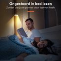 Man leest in bed met verstelbare lamp, partner slaapt.