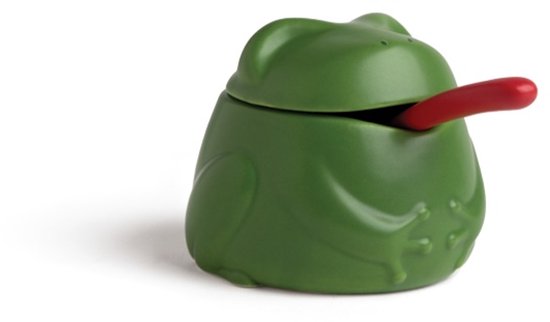 Groene kikkerzoutpot met een rode lepel die uit de mond steekt, op een witte achtergrond.