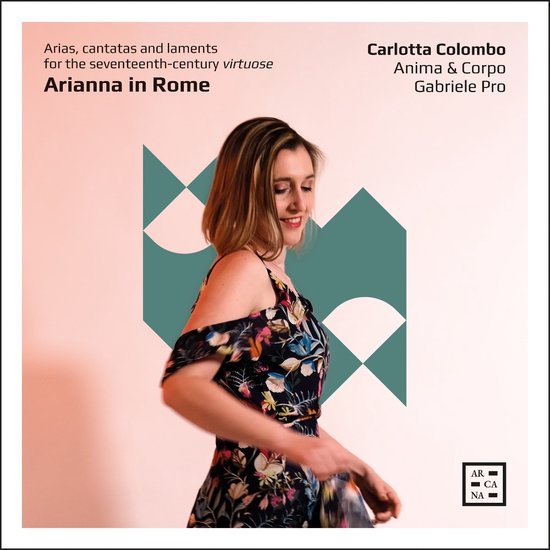 Carlotta Colombo in een jurk met bloemenprint, met blote schouders, draait weg van de camera, met grafische patronen op de achtergrond.