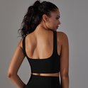 Draai om naar achteren kijkend model in zwart sporttopje met vierkante halslijn en racerback bandjes.