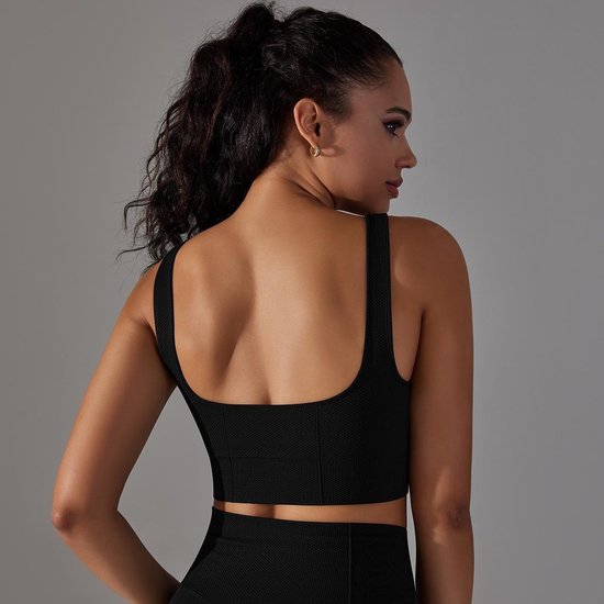 Draai om naar achteren kijkend model in zwart sporttopje met vierkante halslijn en racerback bandjes.