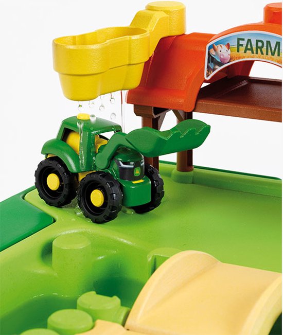 Gedetailleerde close-up van de John Deere boerderij speeltafel met een groene tractor onder een gele watergoot.