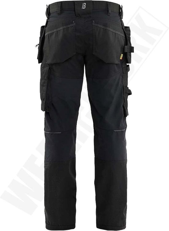 Arrière d'un pantalon de travail noir avec de nombreuses poches et détails réfléchissants.