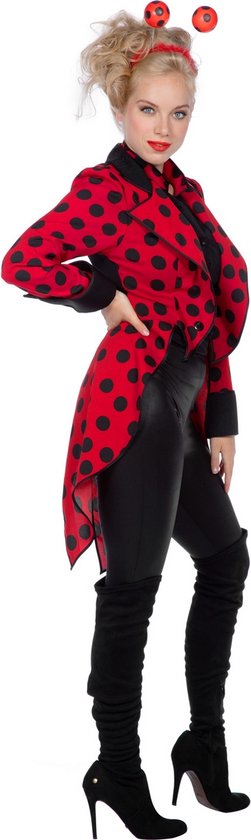 Achterkant van vrouw in rode met zwarte stippen jas, zwarte blouse, leren broek en laarzen. Rode antenne met bolletjes op haarhoofd.