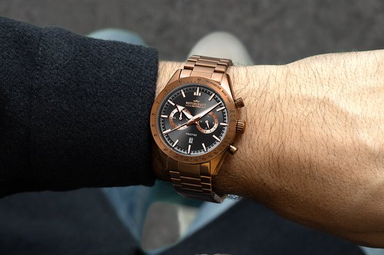 Close-up van een rosegouden Rotorcraft horloge met zwarte wijzerplaat om de pols.