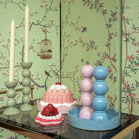 Blauwe en roze peper- en zoutmolens met bolvormige secties, naast een roze jelly dessert.