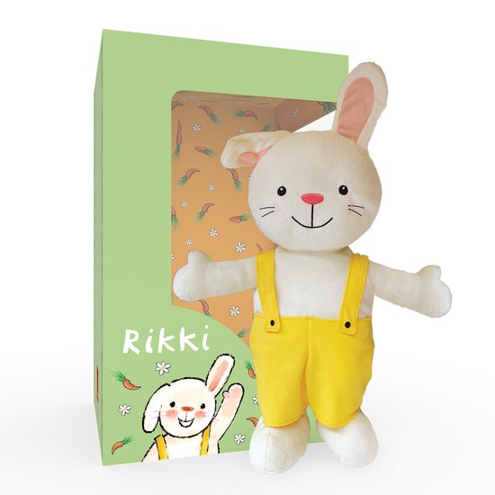 Wit pluche konijn 'Rikki' met gele tuinbroek, staand naast een groene verpakking met wortels en bloemen.