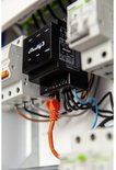Zwarte Shelly Pro 3 DIN-railrelais met oranje LAN-kabel aangesloten in een schakelkast.