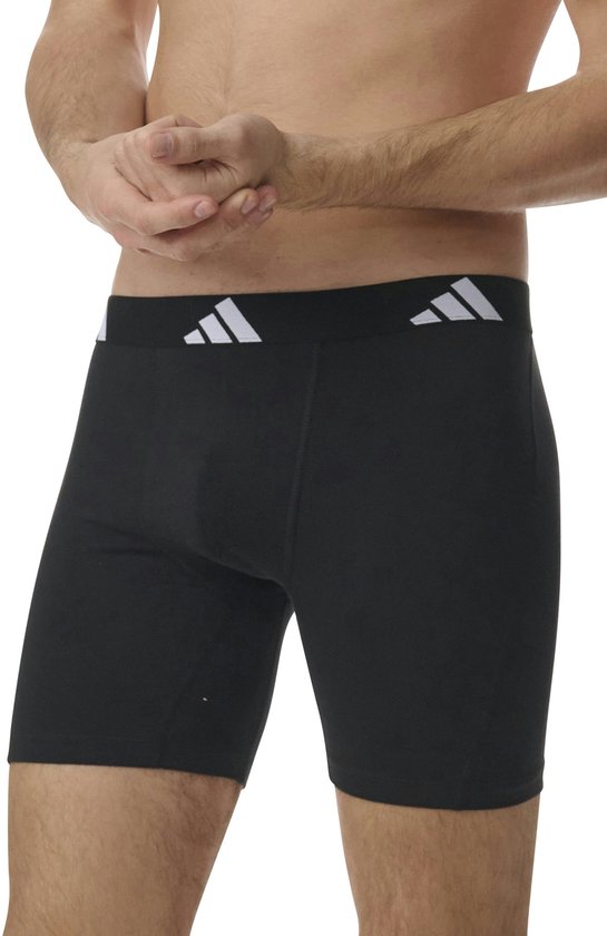 Man in zwarte Adidas boxershorts met zwarte tailleband met Adidas logo.