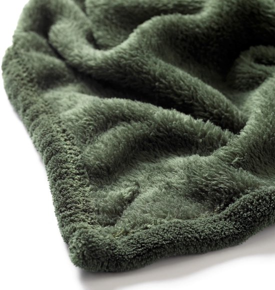 Detail van een donkergroen, zacht fleece plaid met geborduurde rand.