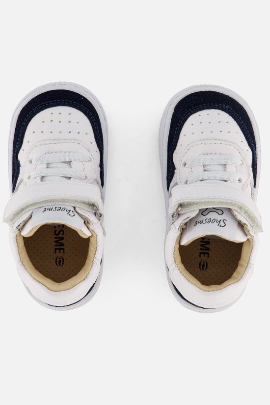 Bovenkant van twee witte leren sneakers met donkerblauwe randen, veters en klittenbandsluitingen. SHOESME op binnenzolen.