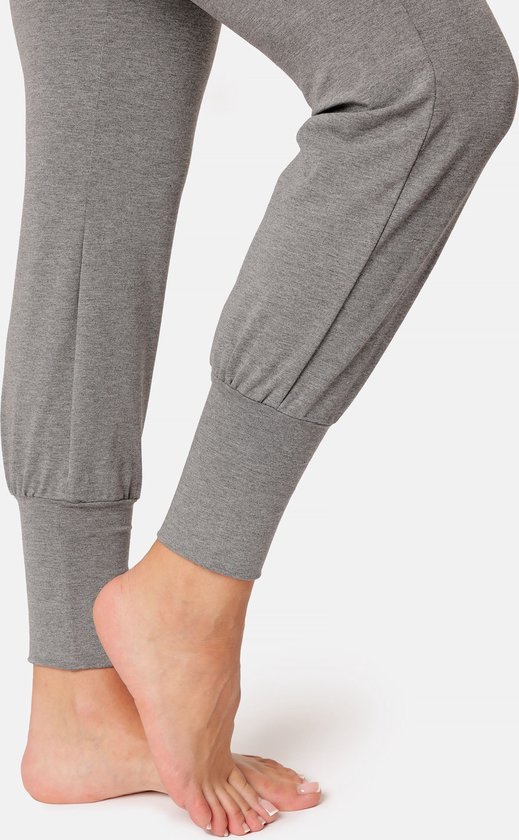 Close-up van de enkels en voeten van een vrouw in grijze yogabroek met gedetailleerde zoom.