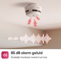 Witte rookmelder aan het plafond met rode bliksem die een geluidssignaal van 85 dB aangeeft. 85 dB alarmgeluid, duidelijk hoorbaar in je huis.