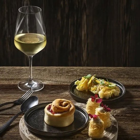 Elegante witte wijn en gebak op een rustieke houten tafel. Twee glazen met witte wijn, bestek en servetten.