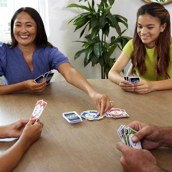 Een gezin speelt DOS aan een tafel, met kaarten en spelonderdelen verspreid.