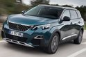 Een tealgroene Peugeot 5008 rijdt over een weg, gezien vanaf de voorkant rechts. De auto heeft getinte ramen en zilverkleurige accenten.