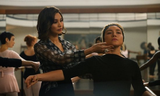 Danseres in witte jurk krijgt instructies van instructrice in zwart.
