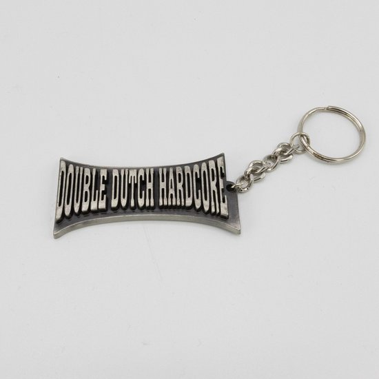 Zilverkleurige sleutelhanger met 'DOUBLE DUTCH HARDCORE' tekst in reliëf, verbonden door een ketting.