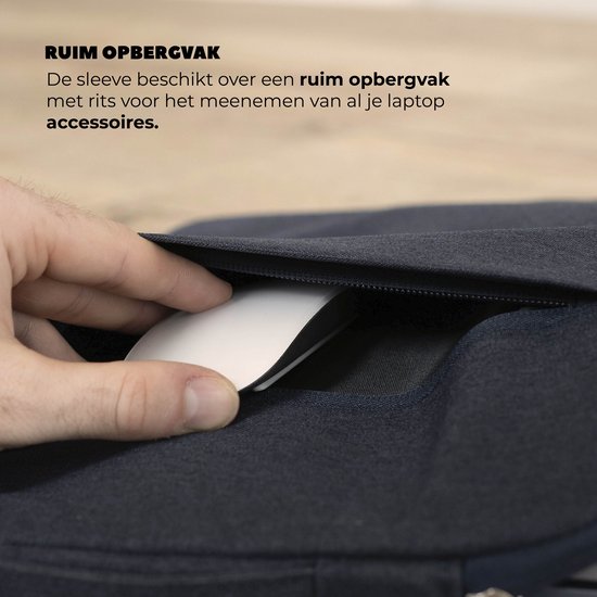 Hand haalt een muis uit het ritsvak van een donkerblauwe laptoptas.