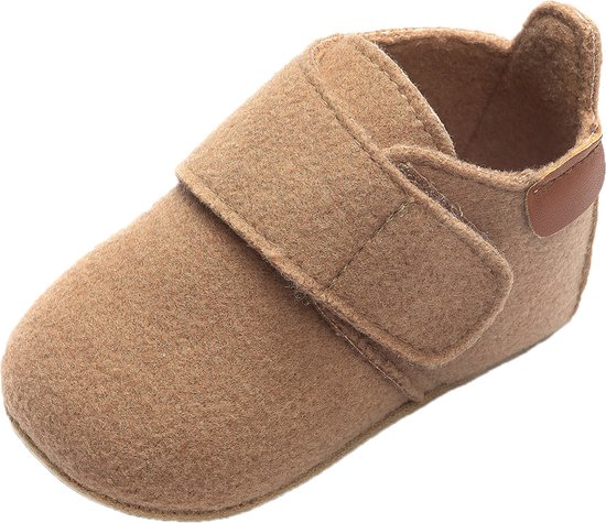 Zijaanzicht van een lichtbruin babyslofje met klittenbandsluiting en bruine leren details op de hiel.