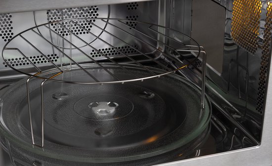 Binnenkant van een inbouwmagnetron met glazen draaiplateau en metalen grillrooster.