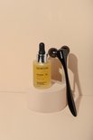 Glazen flesje SKINONE vitamine C serum met druppelaar en een zwarte dermaroller met twee wieltjes.