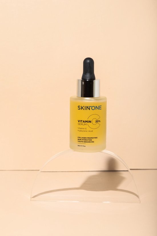 Glazen flesje SKINONE vitamine C serum met druppelaar op een transparante ronde standaard.