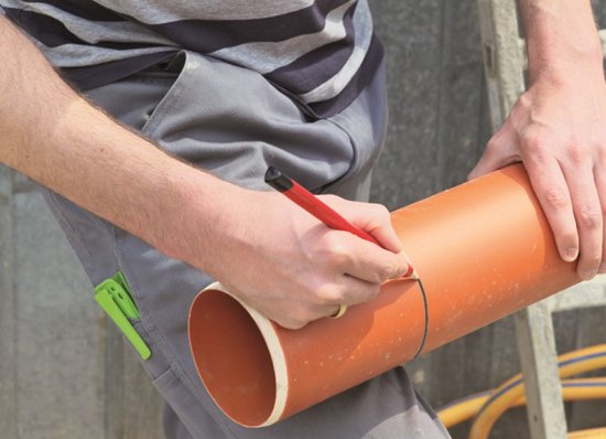 Hand tekent met rood potlood een lijn op een oranje pvc buis.