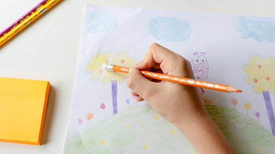 Hand kleurt met een oranje BIC Kids Illusion potlood een boom, naast gele post-its.