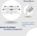Afbeelding met een close-up van een witte wasmachineverhoger met lades en een detail van een deurpost.