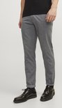 Model in grijze broek met subtiel visgraatpatroon, zwarte schoenen en sokken.