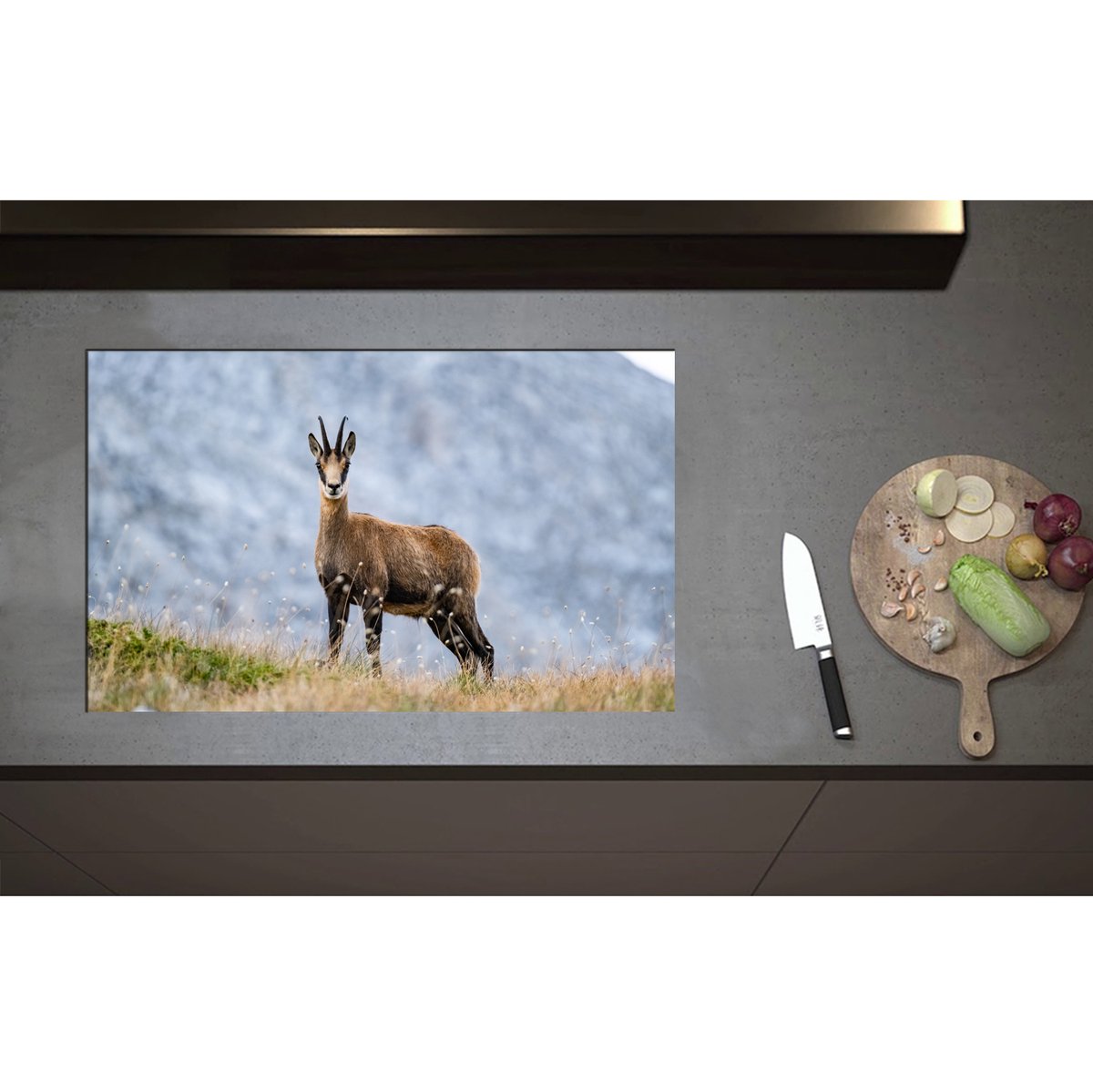 Inductieplaat Beschermer - Aankijkende Wilde Geit in het Gras aan de Rand van Bergen - 80x50 cm - 2 mm Dik - Inductie Beschermer - Bescherming Inductiekookplaat - Kookplaat Beschermer van Zwart Vinyl