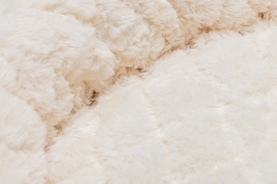 Close-up van de zachte, beige pluche stof van een kattenmand met een ruitpatroon.