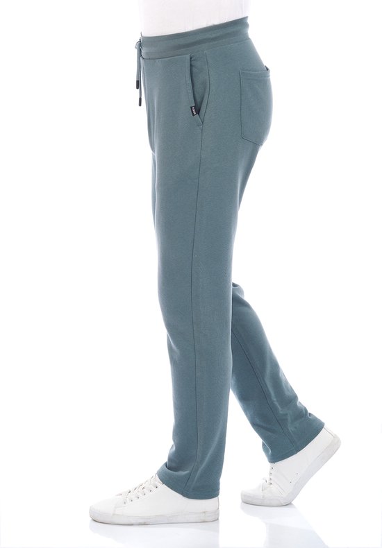 Zijzicht van een man in een donkergroene joggingbroek met trekkoord en witte sneakers.